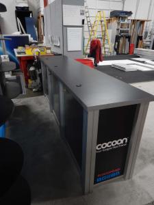RENTAL: Modified RE-1010 with Custom Rectangular Counter, Custom Black Laminated Shelves, Halogen Arm Lights, Tension Fabric Graphics, and Sintra Infill Graphics for Counters -- Image 3
