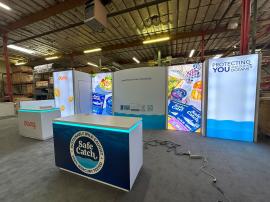 RENTAL: Custom 10' x 25' Inline Design with Gravitee System Storage Closet, Curved Gravitee System Panels, (3) Single-Sided Lightboxes, Left Side Half Wall, Bump-Out Panels, RE-1576 White Laminated Reception Counter, RE-1577 White Laminated Reception Coun
