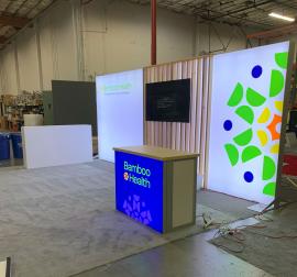 RENTAL: Inline Design with Single-Sided Lightbox, Large White Laminated Planter Box, and (2) Small Planter Boxes, RE-1567 Backlit Reception Counter with Hard Rock Maple Top, Custom Slatted Wood, Large Monitor Mount, 65" Monitor, and SEG Fabric Graphics