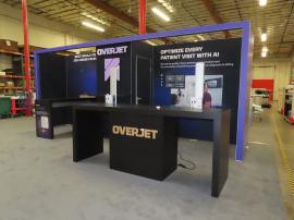 Modified GK-2019 Gravitee Inline Exhibit with Tension Fabric Graphics, Push Thru Backlit Acrylic Logos, Shelves, Monitor Mounts, Locking Closet Storage, Modified MOD-1734 Genius Bar, and Modified MOD-1707 Parsons Counter with Storage