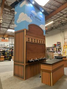 RENTAL: Island Rental Design with RE-1712 Gravitee Storage Tower with Locking Door, 72"  x 10" Black Laminated Shelf, RE-1207 Large Rectangular Counter, RE-1202 Workstation Counter, L-Shaped Double-Sided Gravitee Wall @ 92" x 92" x 95" High, (2) Double-Si